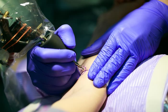 Tattoo artist creating a tattoo with multiple circles.