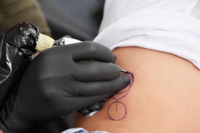 Tattoo artist creating design with multiple circles.  A circle tattoo meaning can be far more complex than its simplistic shape initially suggests.