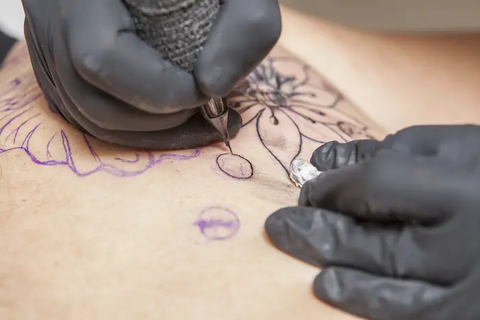 A tattoo artist creating a circle shape as part of a larger tattoo design.