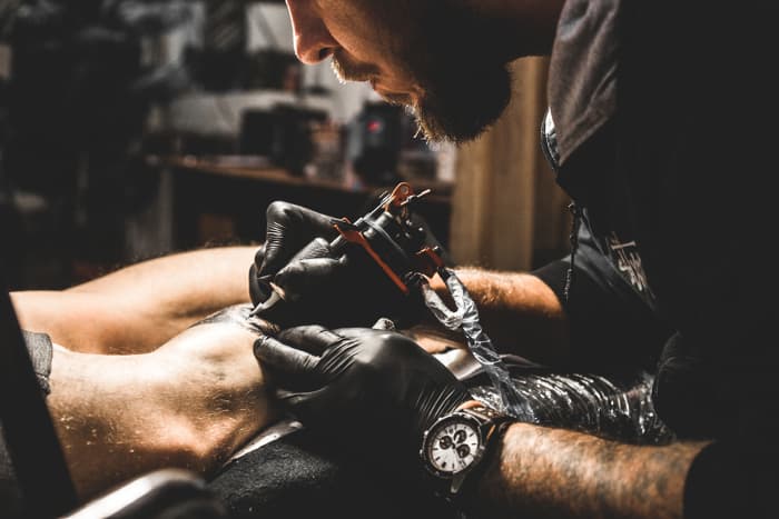 A tattooist working on a client's arm.