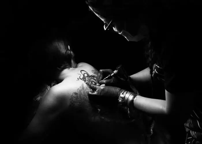 A tattooist working on a client's back.