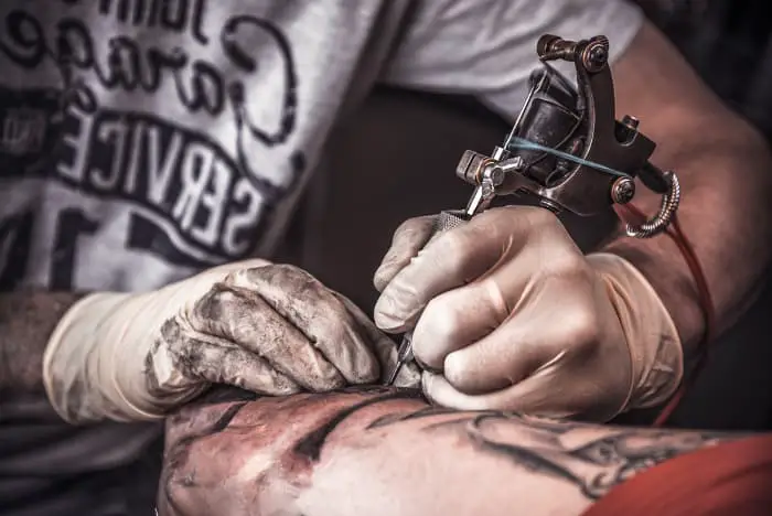 A tattooist working on a client.
