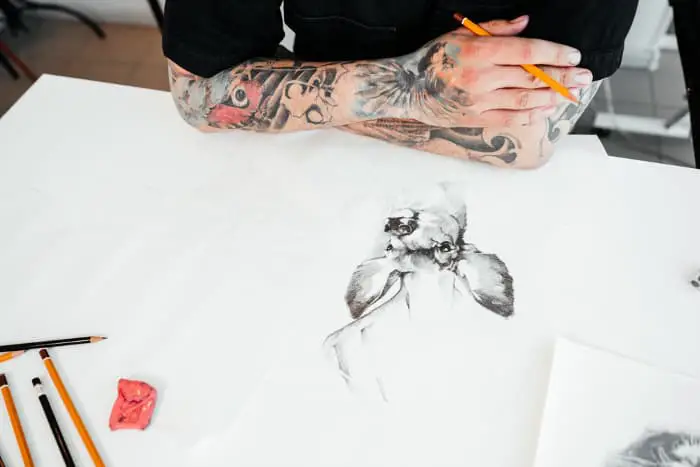 A tattooist sketching a tattoo image of a deer.