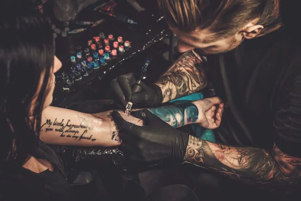 A tattoo artist working on an arm tattoo.