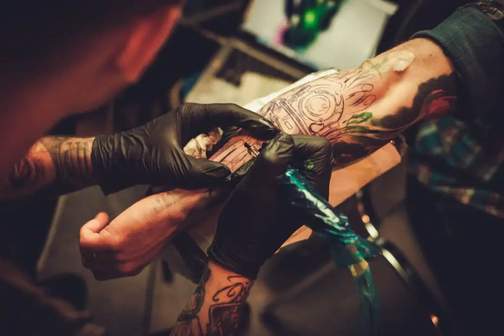 A tattoo artist working on a client's arm.