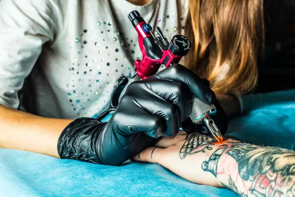 A tattoo artist working on a client's hand.