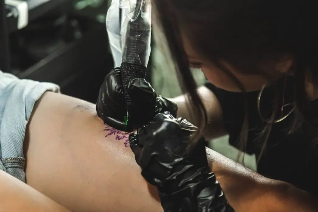 A tattoo artist working on a tattoo.