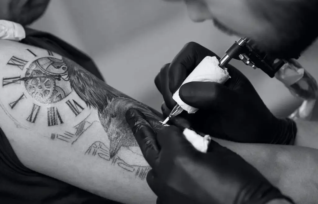 A tattoo artist working on a crow tattoo design.