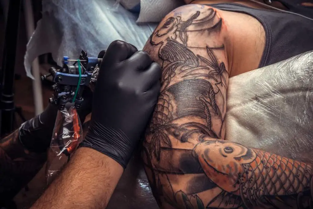 A tattoo artist working on a client's arm.