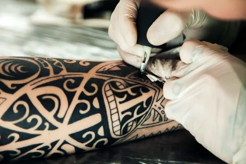 A tattoo artist working with black ink.