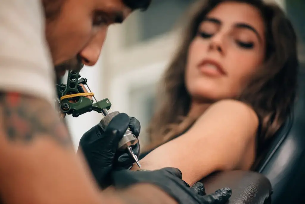 Woman gettingn a tattoo on her arm.