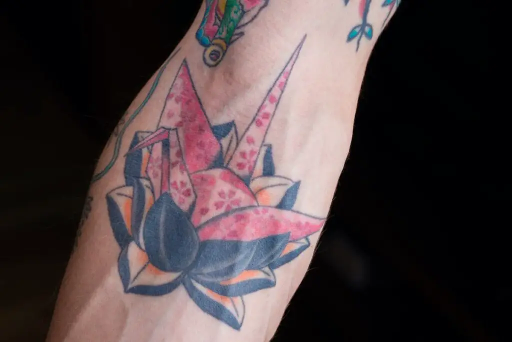 A colorful origami-style paper crane tattoo.