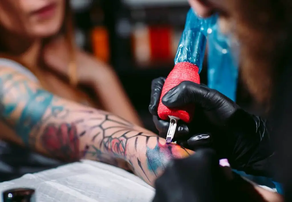 Tattoo artist working on woman's arm.