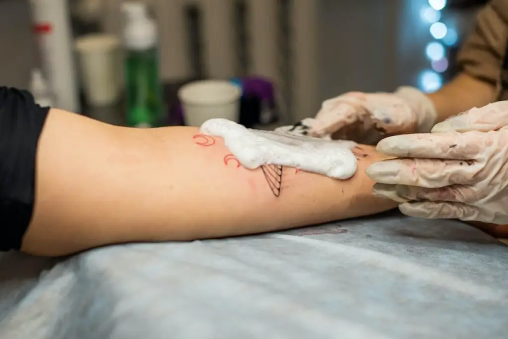 Tattoo artist washing new tattoo work.