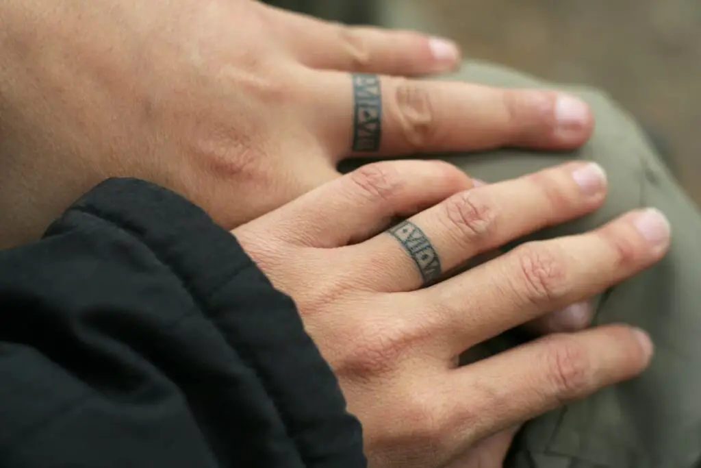 A couple with matching wedding ring finger tattoos.