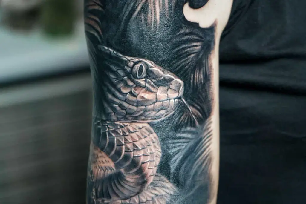 Closeup of a snake tattoo in realism style. Does a snake tattoo meaning fit you and your beliefs?