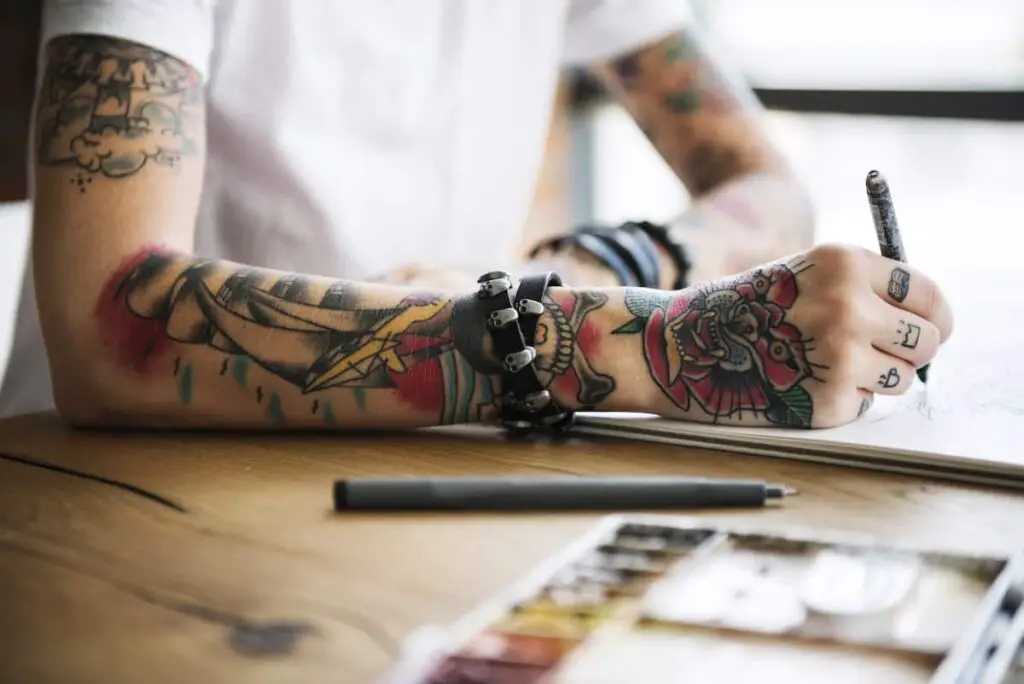 Cheerful bearded tattoo artist laughing, talking to his female client while  showing her tattoo sketches. Beautiful woman choosing new tattoo sketch at  Stock Photo - Alamy