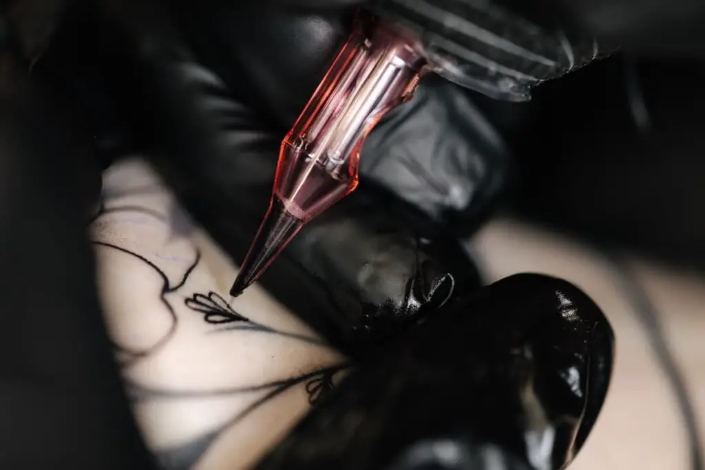 Closeup of tattoo artist using tattoo gun to ink design.