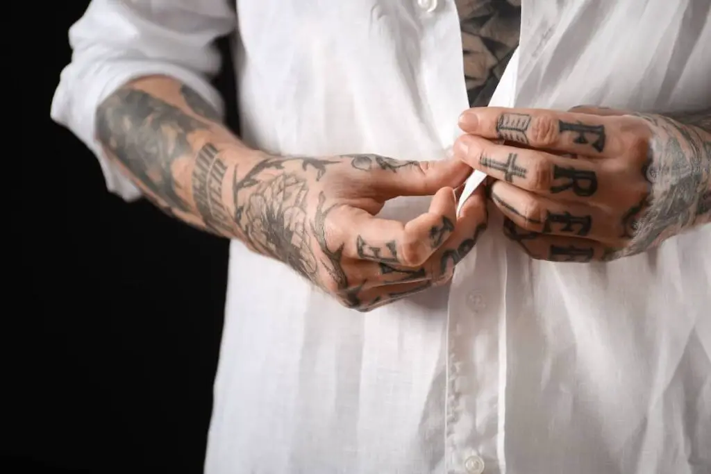 Man with black ink tattoos on hands and forearms.