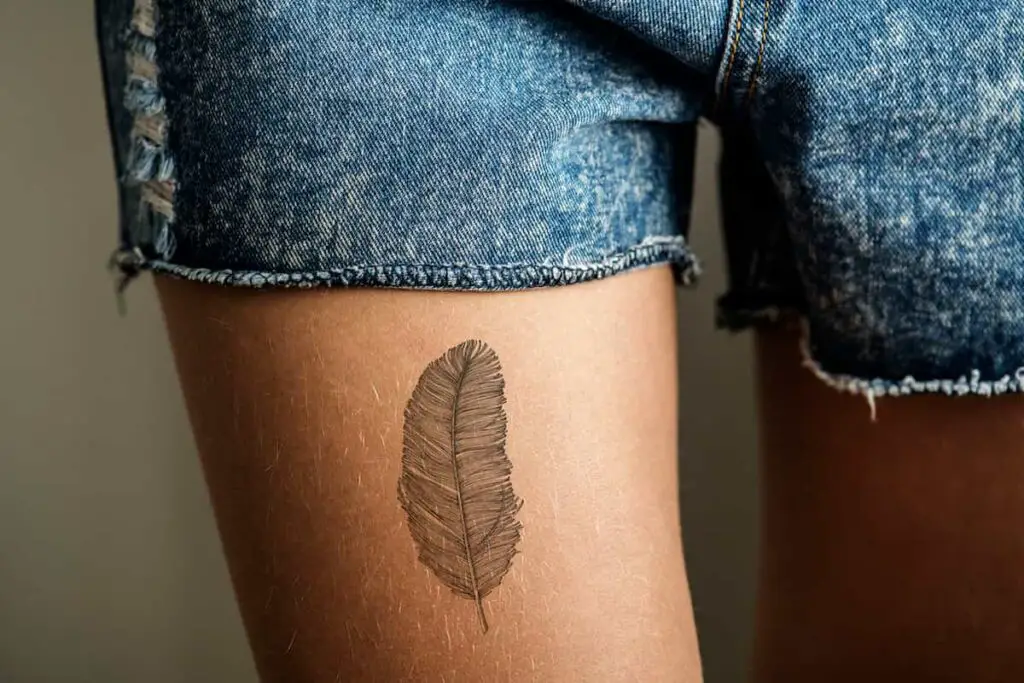 A feather tattoo on a woman's thigh.