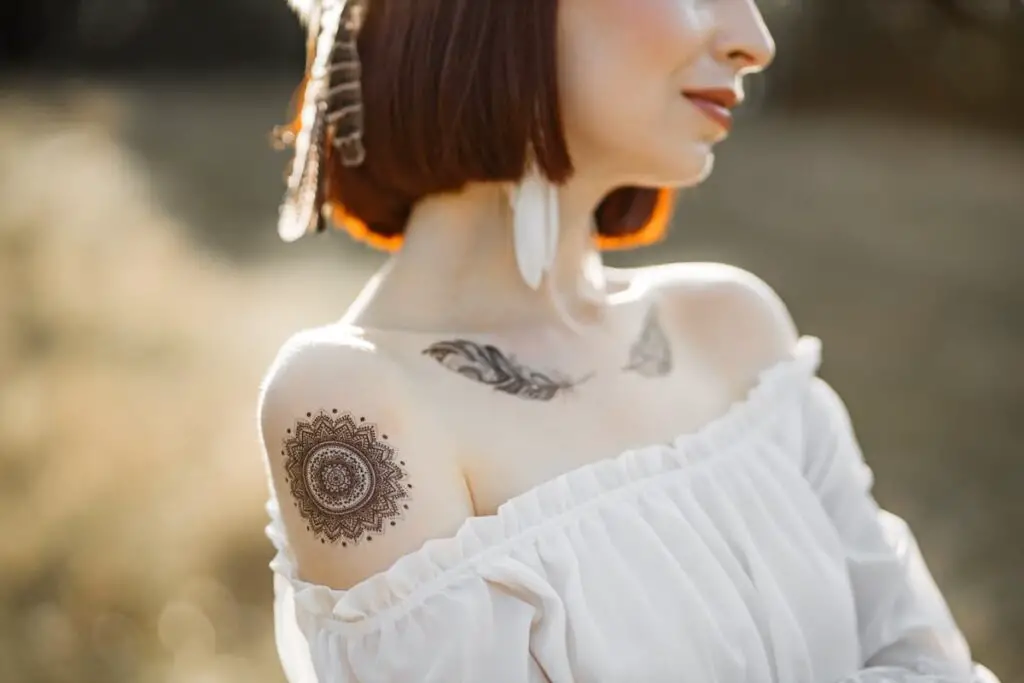 A woman with feather tattoos beneath her collarbones.