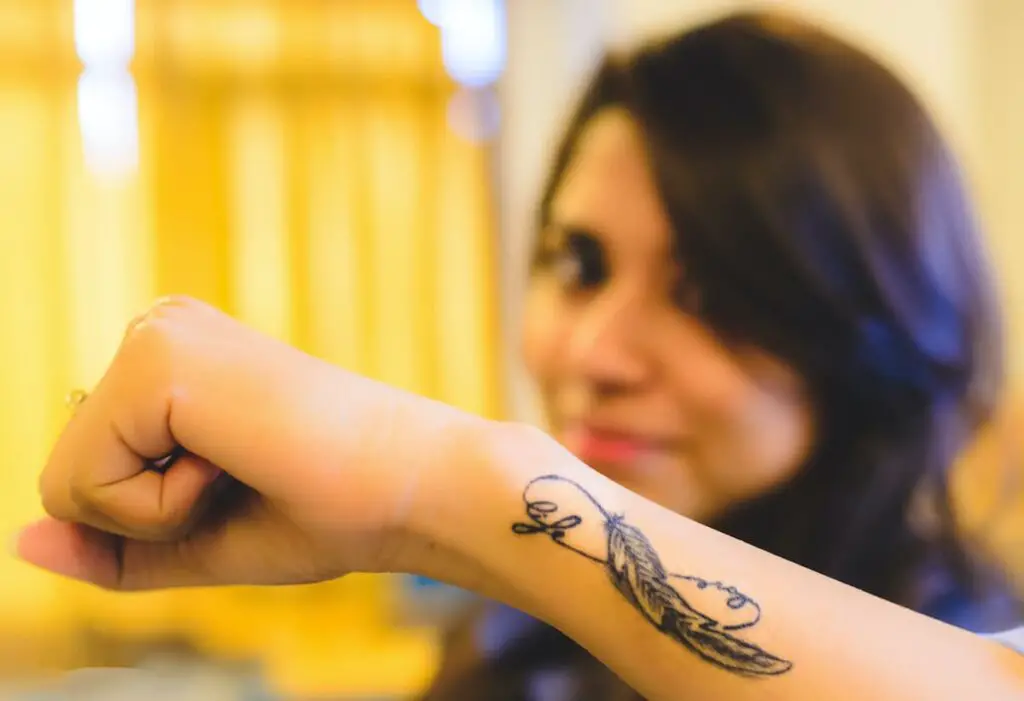 An infinity feather tattoo on a woman's forearm.