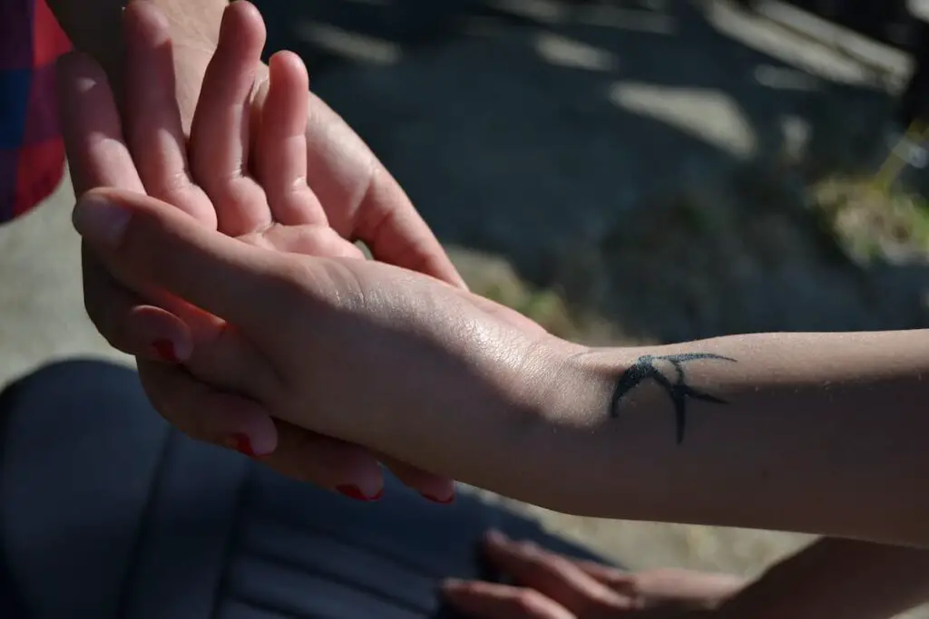 A small swallow tattoo design on a woman's inner wrist.