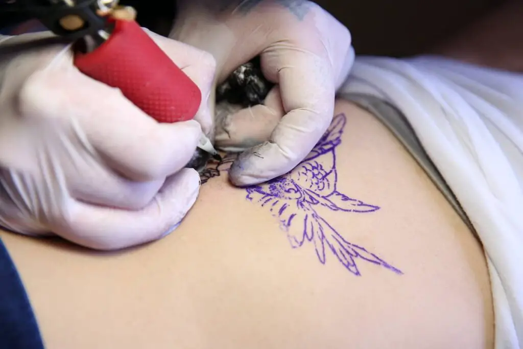 A tattoo artist creating an owl tattoo.