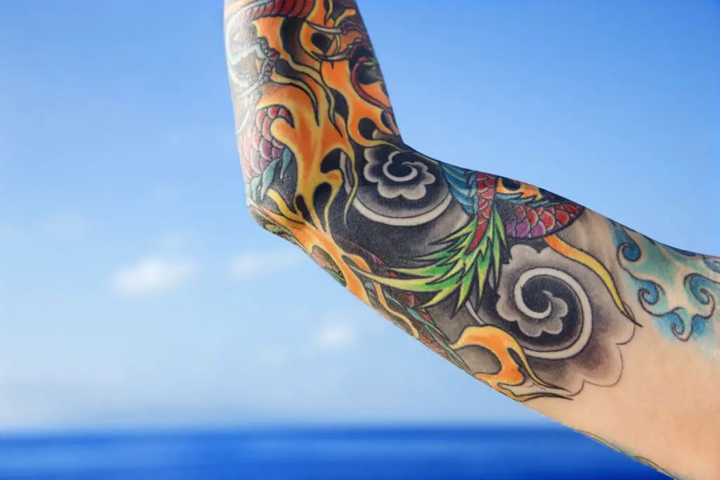 A dragon tattoo on an arm with a blue sky in the background.