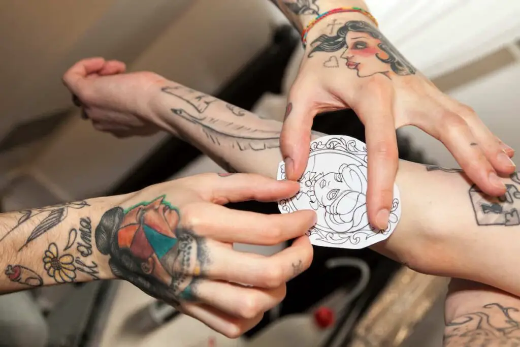A tattoo artist placing a tattoo stencil on a person's arm.