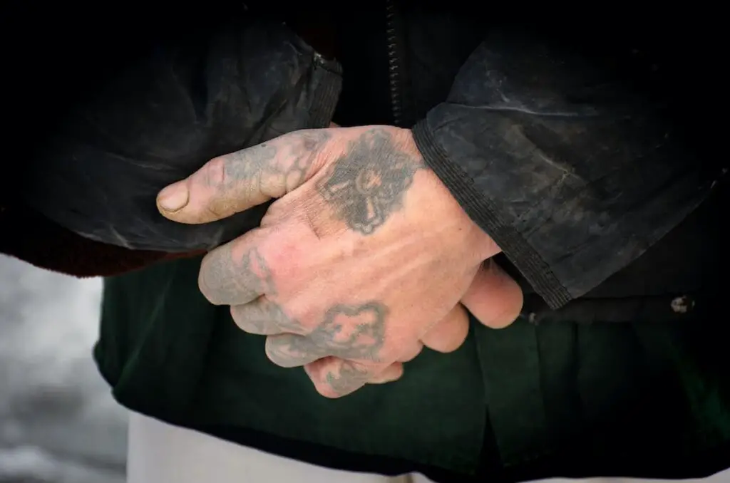 Man's hands with faded tattoos on them.
