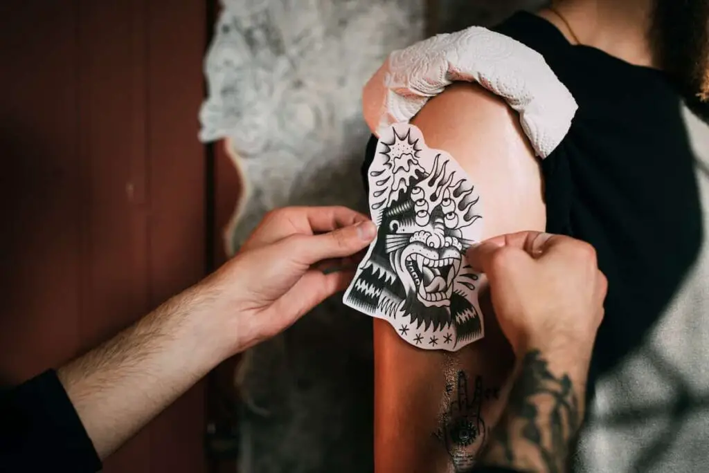 A tattoo artist placing a stencil of a tattoo.