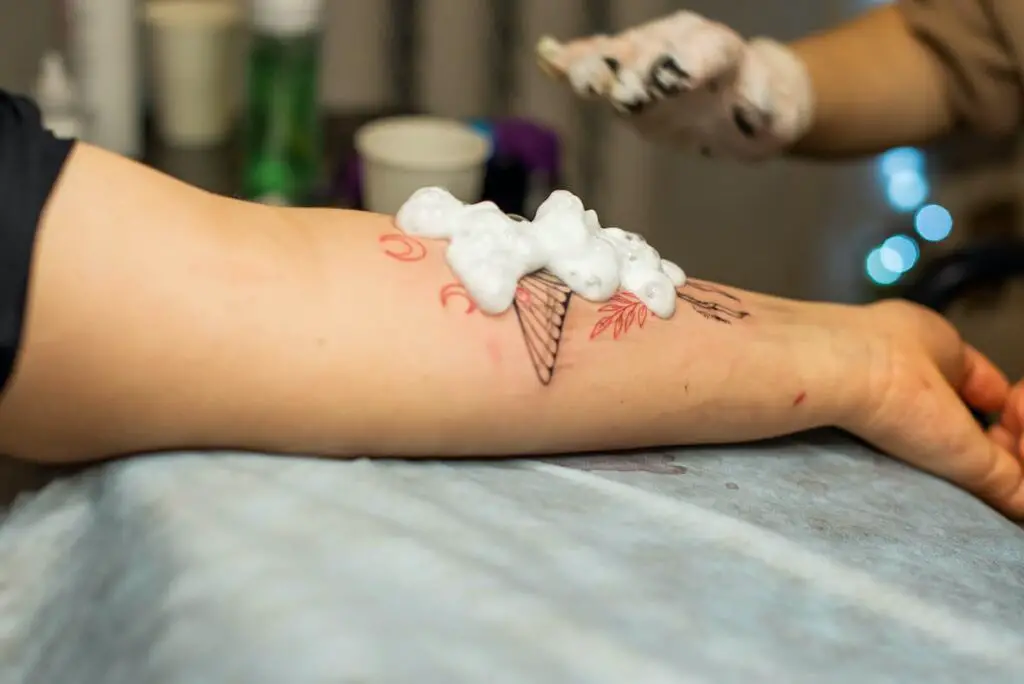 Tattoo artist using soap on new tattoo work.