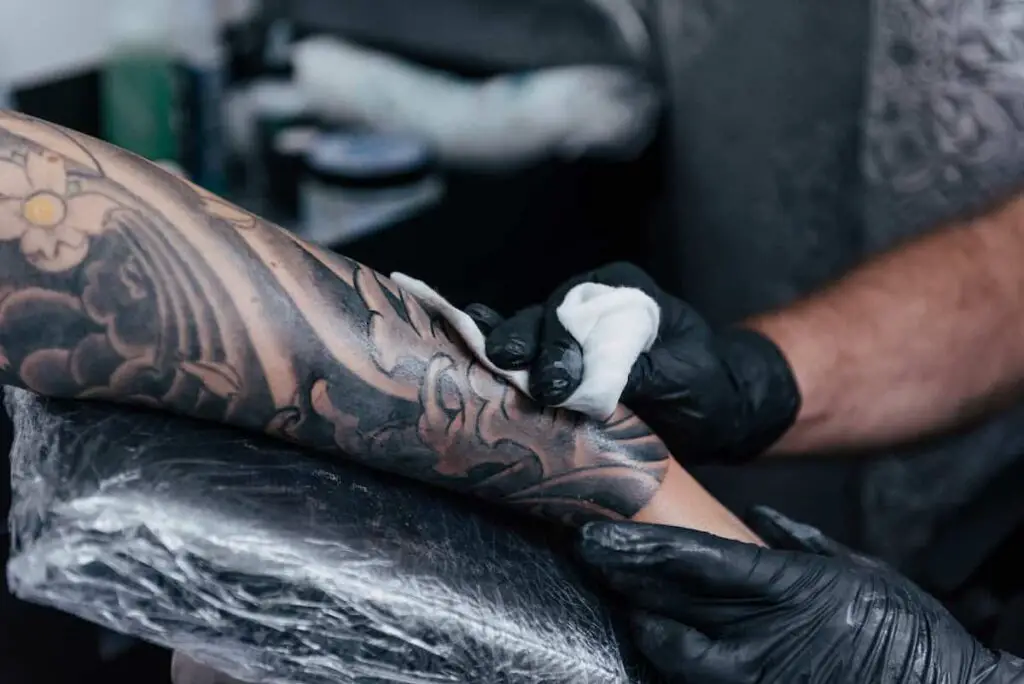 Tattoo artist working with gray tones and muted colors.