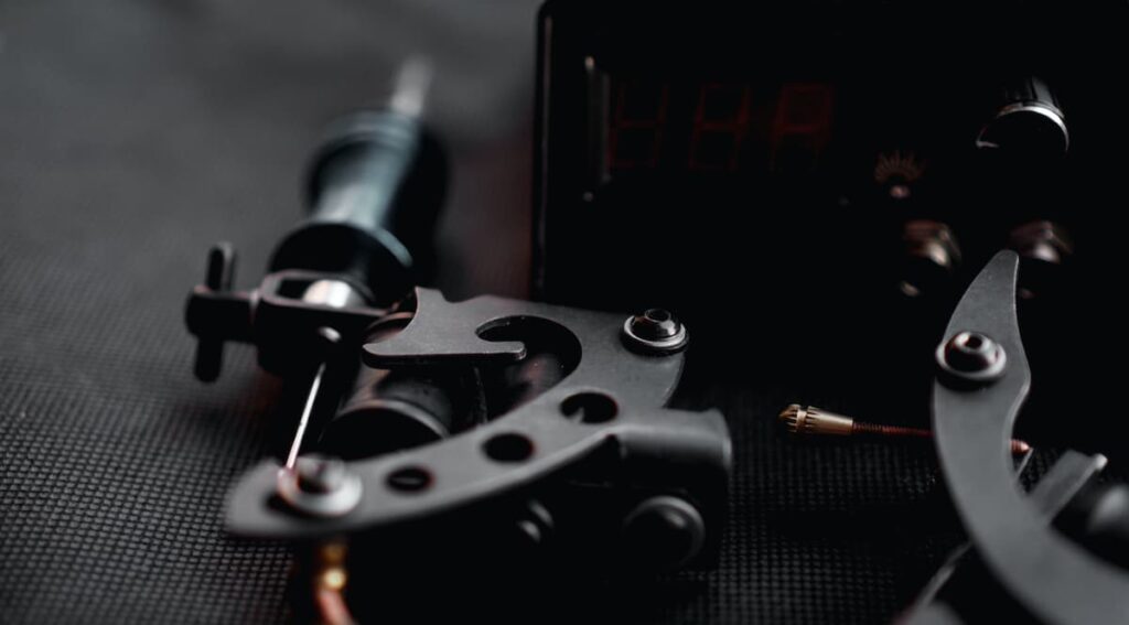 Closeup of a tattoo gun and a tattoo power supply machine.