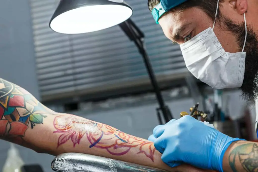 A tattoo artist using an adjustable lamp while working on a client.