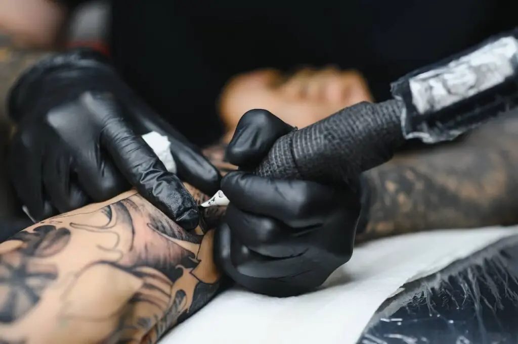 Closeup of a client's arm on an arm rest while a tattoo artist works.